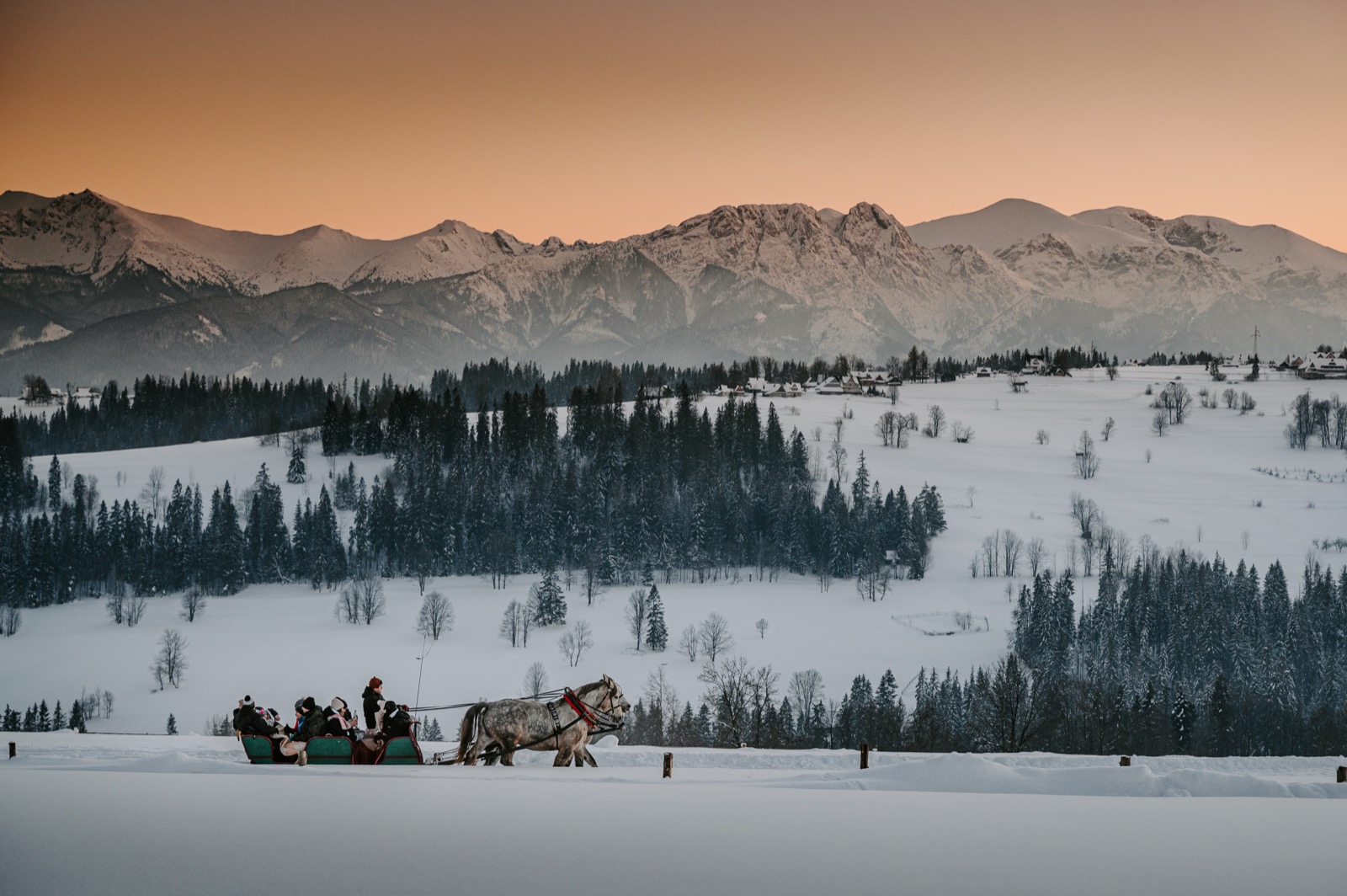Zimowa panorama Tatr z saniami na śnieżnym szlaku